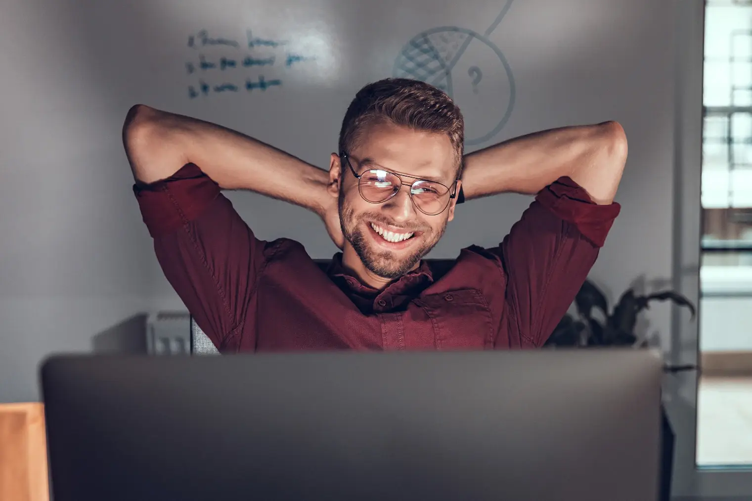 Creative motion designer smiling in front of his laptop because his team has finally implemented Scrum methodology