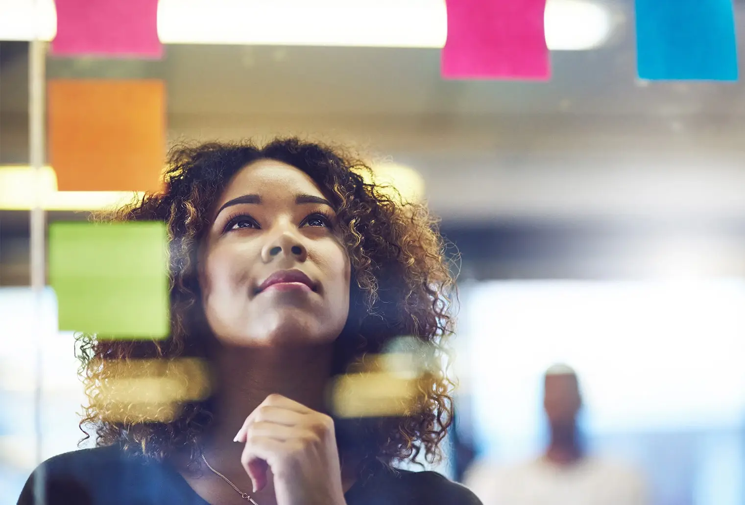 Creative operations manager standing in front of a glass window and looking at sticky notes