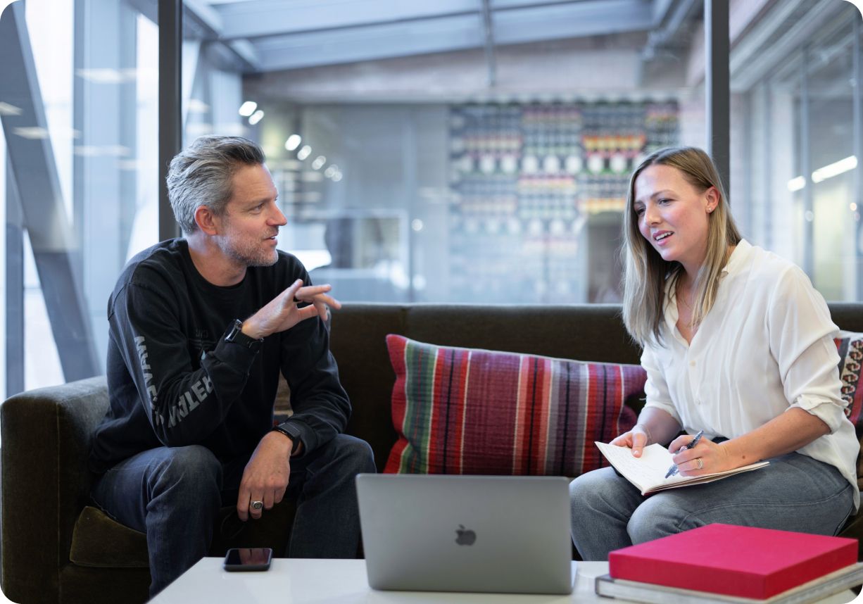 Creative project managers discussing company vision on sofa next to laptop and table