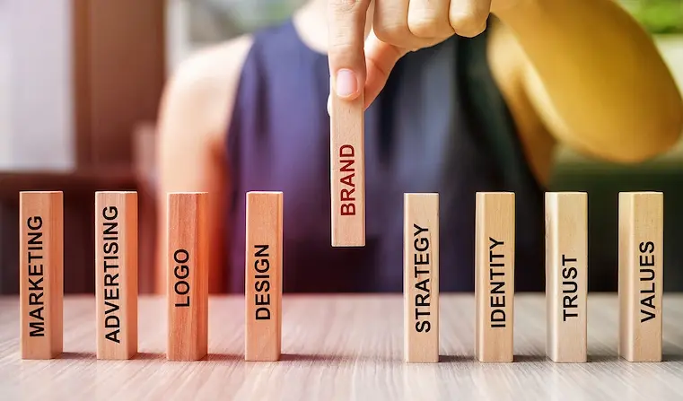 Man organizing wooden blocks with Marketing, Advertising, Logo, Design, Brand, Strategy, Identity, Trus and Values words
