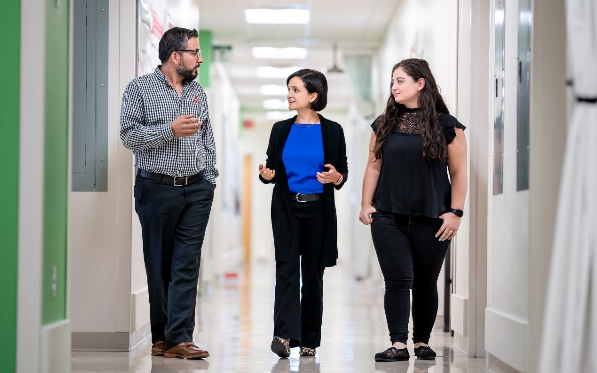 St Judes research hospital employees walking by the corridor and discussing - two women and a man adults