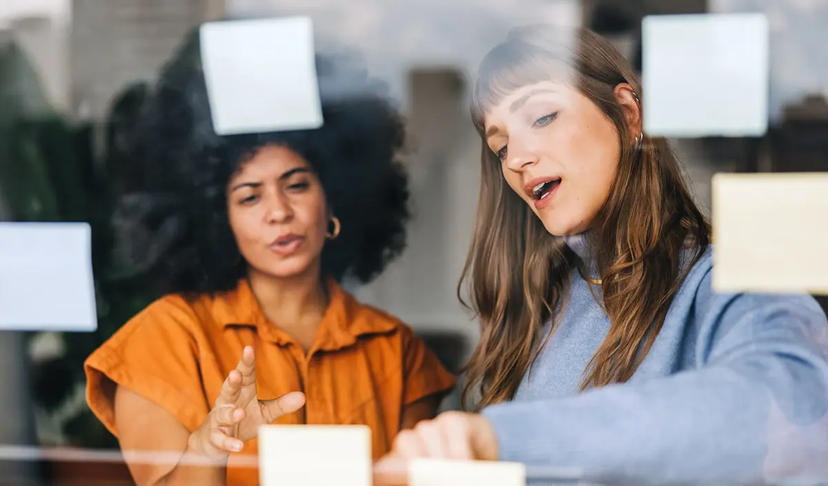 Two business professionals discussing company rebranding strategy by the cafe window desk