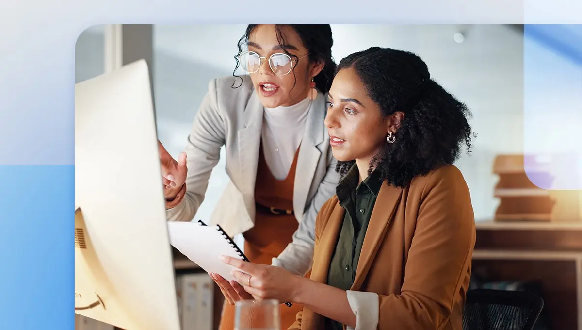 Web design team discussing design feedback in front of a desktop computer