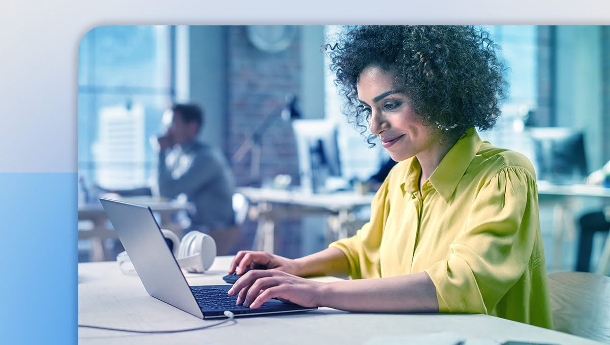 Woman working in an office by her laptop and smiling